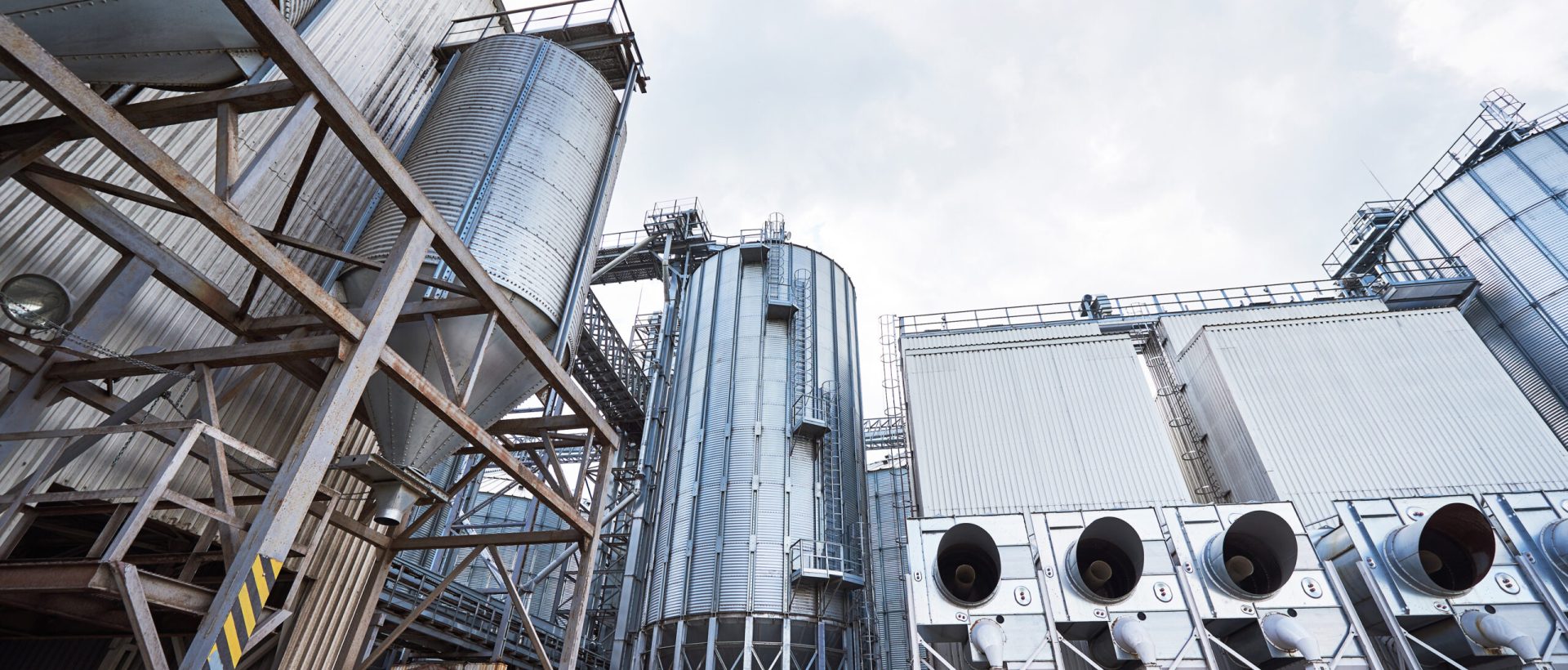 Agricultural Silos. Building Exterior. Storage and drying of grains, wheat, corn, soy, sunflower against the blue sky with white clouds.